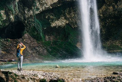 Woman hiker looking up at the top of hidden waterfall