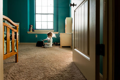 Boy playing with steam machine while sitting on rug at home seen through doorway