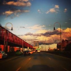 Road passing through city against cloudy sky