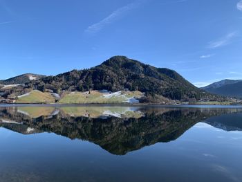 Scenic view of lake and mountains against blue sky