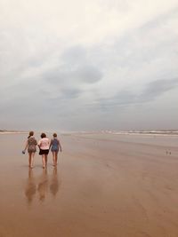 Rear view of people walking on beach