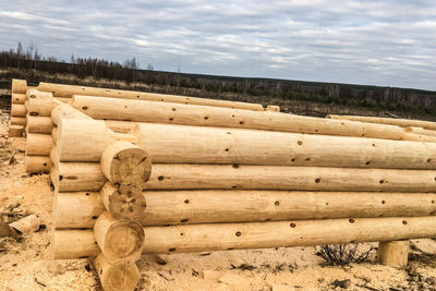 Stack of logs on field against sky