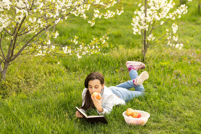High angle view of girl eating apple lying on grass at park