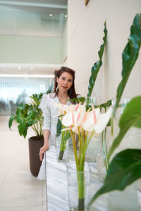 Beautiful woman standing by potted plant