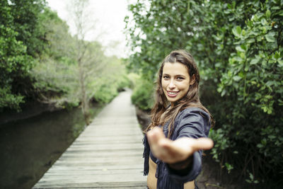 Portrait of smiling young woman standing against plants