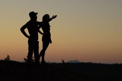 Silhouette men standing on land against sky during sunset