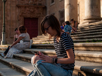 Full length of woman sitting on staircase