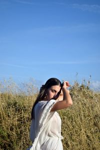 Young woman standing on field against clear blue sky