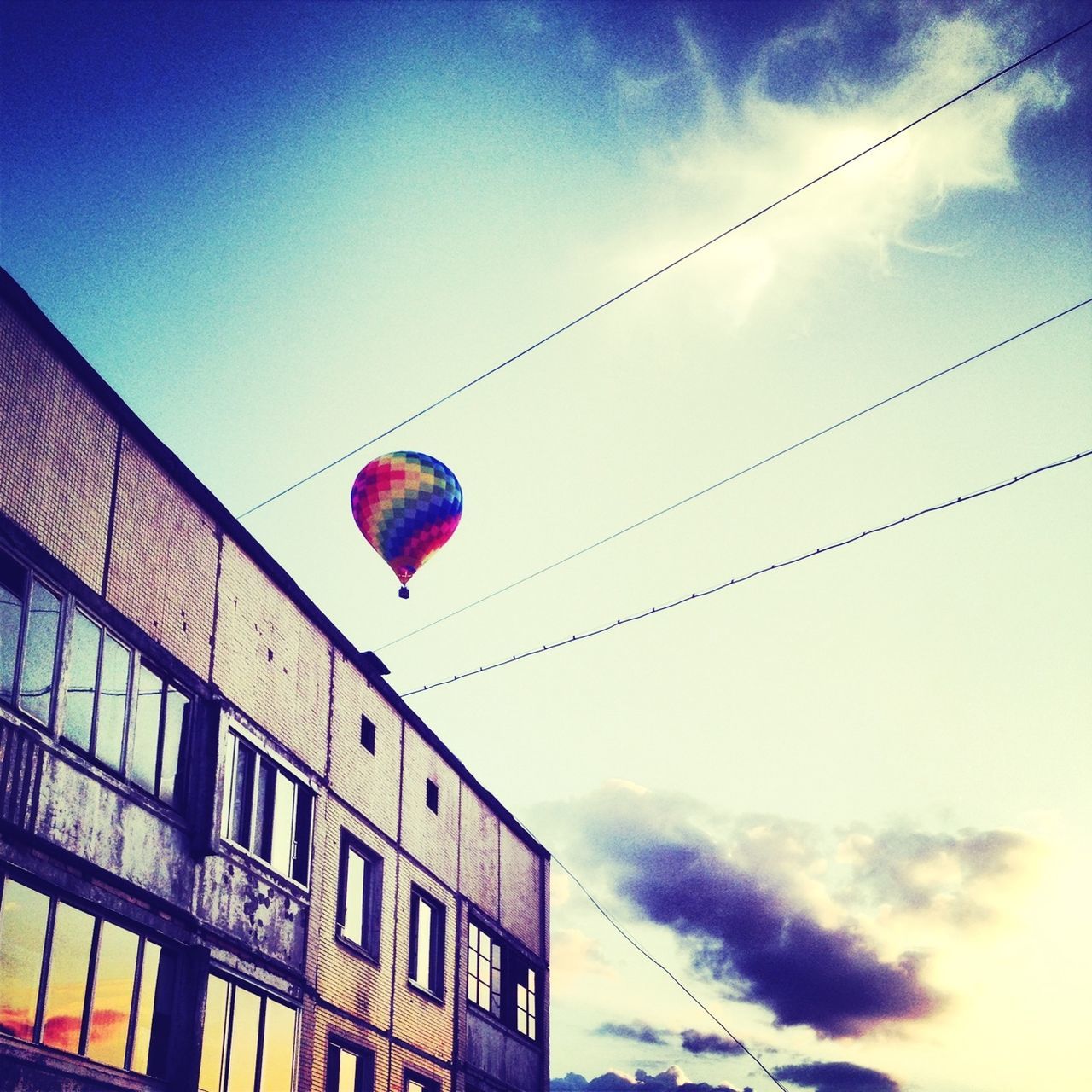 low angle view, hanging, building exterior, architecture, built structure, sky, lighting equipment, balloon, cable, street light, blue, multi colored, lantern, power line, electricity, outdoors, decoration, day, road signal, celebration