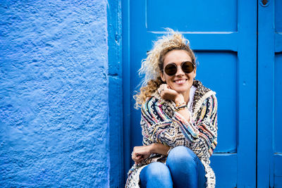 Portrait of a smiling young woman sitting at entrance