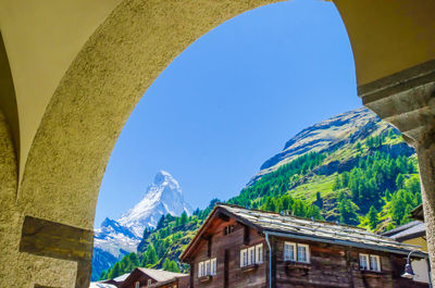 Low angle view of buildings and mountains against clear blue sky