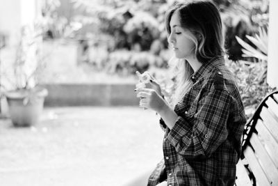 Woman holding bubble wand while sitting on bench