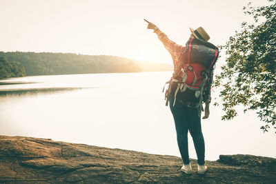 Rear view of man standing by lake against sky