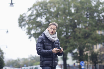 Mature man using smart phone on street