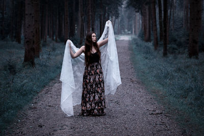 Young woman with white fabric standing on pathway