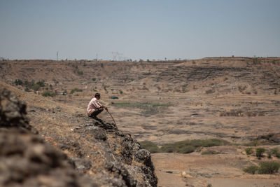 This man is in the middle of a drought land and he's praying for good rains.