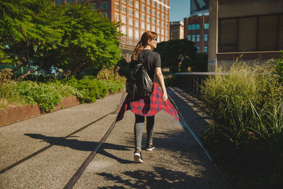  rear view of woman with backpack walking on street