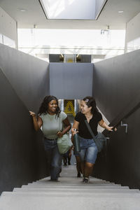 High angle view of happy multiracial friends moving up stairs in university