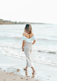 Full length rear view of woman walking on beach