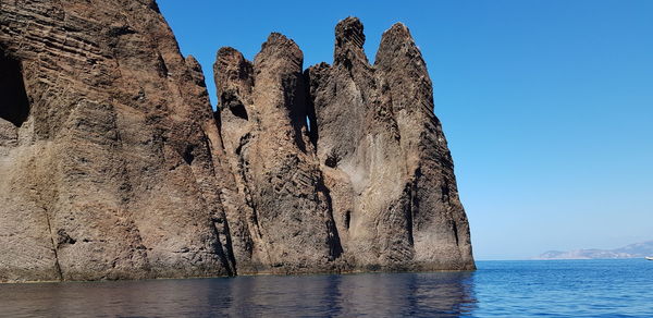 Low angle view of rock formation in sea against clear sky