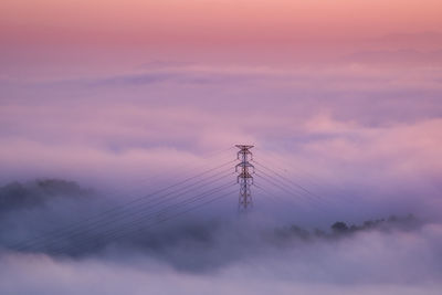 Low angle view of electricity pylon against sky during sunset