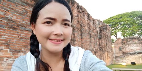 Portrait of woman against brick wall