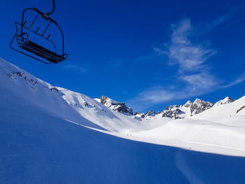 Snow covered mountain range against blue sky