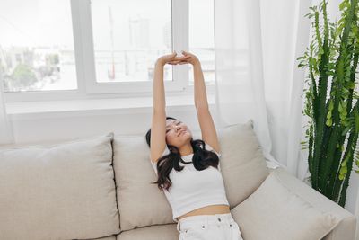 Portrait of young woman sitting on sofa at home