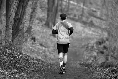 Rear view of man jogging in forest