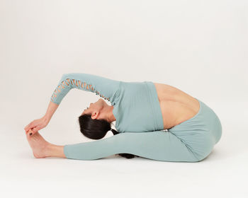 Low section of woman exercising against white background