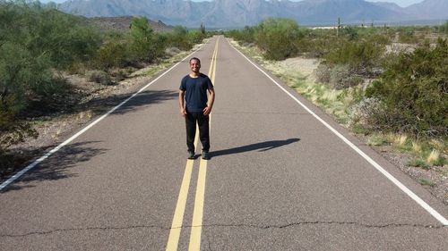 Full length of man standing on road during sunny day