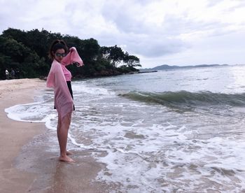 Full length of woman standing on beach against sky