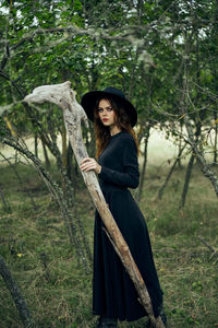 Portrait of young woman standing against trees