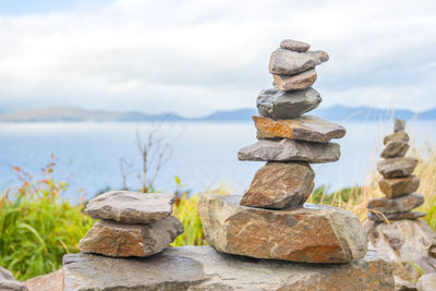 Stack of stones in sea against sky