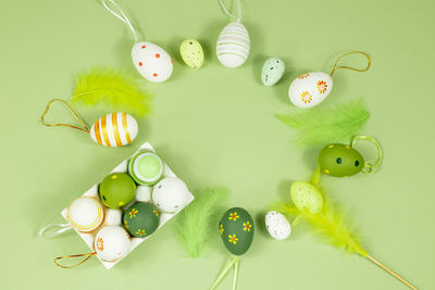 Top view of easter eggs in an egg stand painted with different patterns on a green background.