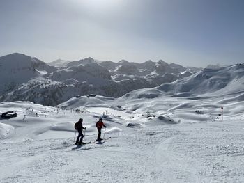 People on snowcapped mountain against sky