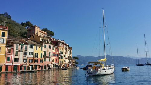 Boats in calm sea against clear blue sky