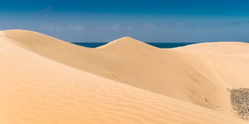 Sand dunes in desert against sky