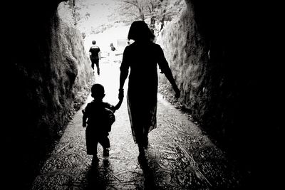 Rear view of mother and son walking in footpath