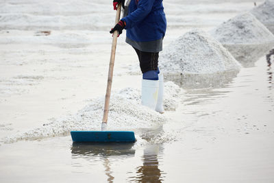 Agriculture using wooden rake harvesting dried salt at salt pan