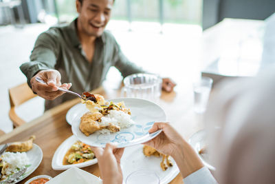 Midsection of woman having food at home