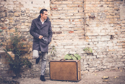 Full length of young man standing against brick wall