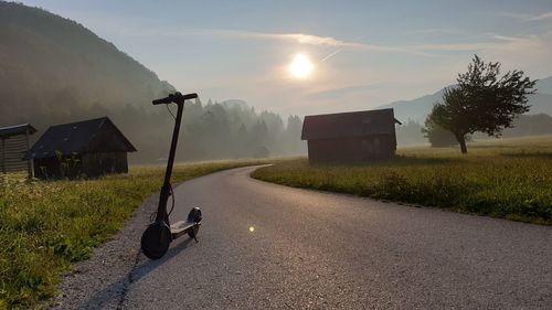 Road amidst field against sky during foggy weather