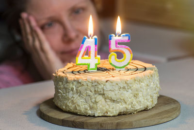 Close-up of woman looking at lit numbers on cake