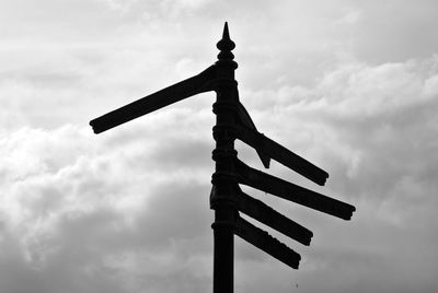 Low angle view of directional sign against cloudy sky