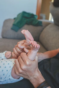 Cropped hand of father holding baby feet at home