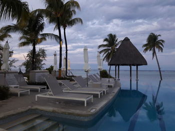 Palm trees by swimming pool against sky