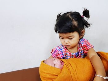 Cute girl carrying sister at home