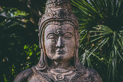 Close-up of buddha statue against trees