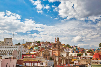 View of buildings in city against cloudy sky